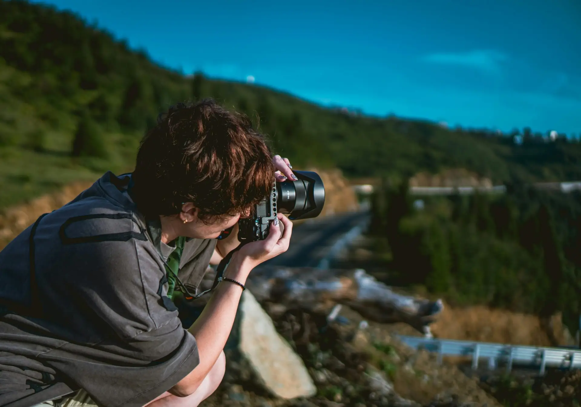 Photographer outdoors capturing a scenic view in a mountainous landscape.